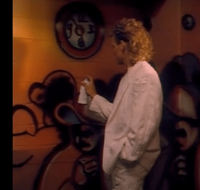 A picture of Gary Lee spray-painting his already graffiti-covered wall.