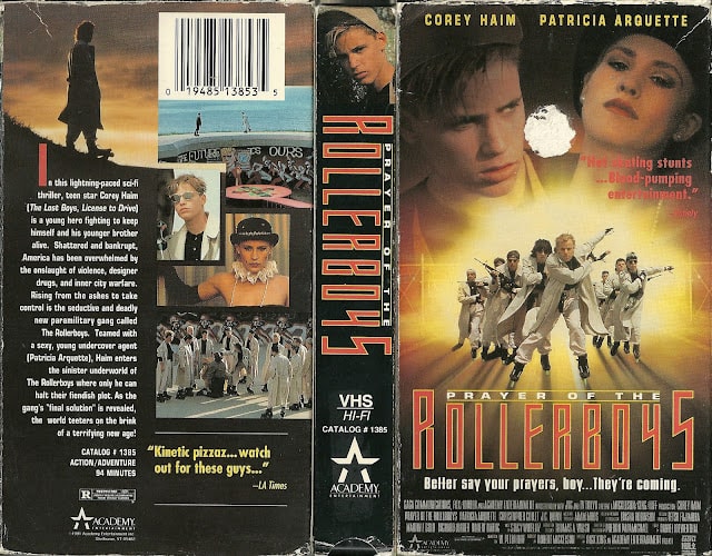 A picture of the film's VHS box, complete with movie description on the back of the box and a dubious endorsement from the LA Times saying, 'Kinetic pizzaz...watch out for these guys...'. The front of the box shows the film title, 'Prayer of the Rollerboys' in stylized font, with a subheading underneath that reads, 'Better say your prayers, boy...They're coming.' There's the image of the Rollerboys skating toward the viewer in their flying V formation, whilst we see a faded Corey Haim and Patricia Arquette at the top of the box. There's another sketchy endorsement on the front that says, 'Hot skating stunts...Blood-pumping entertainment.' from Variety.